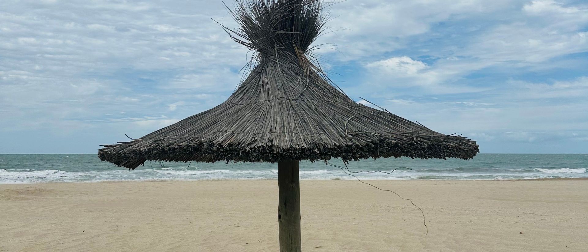 Una sombrilla de paja en la playa vacía
