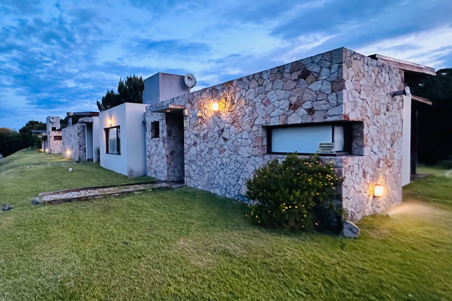 Una casa vista desde el pasto, al atardecer